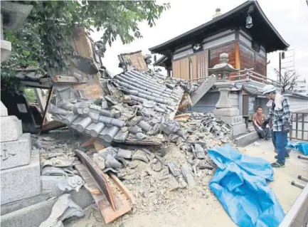  ?? Yosuke Mizuno, Kyodo News via The Associated Press ?? The gate of Myotoku-ji temple collapses after an earthquake hit Ibaraki City, Osaka, western Japan, on Monday. A strong earthquake knocked over walls and set off scattered fires around metropolit­an Osaka on Monday morning.