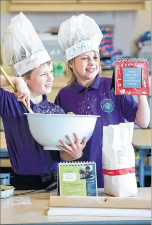  ??  ?? BI-LINGUAL: Calum MacQuarrie and Bethany Gleeson follow the Gaelic-English recipe book. Picture: John Paul