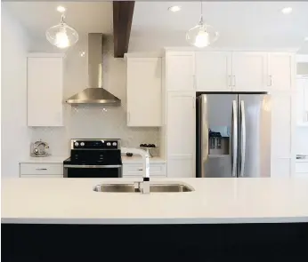  ?? PHOTOS: JENNIFER JACOBY-SMITH ?? White cabinetry, quartz countertop­s and striking tile backsplash offer modern appeal in the stylish kitchen, while a wood beam adds visual interest.