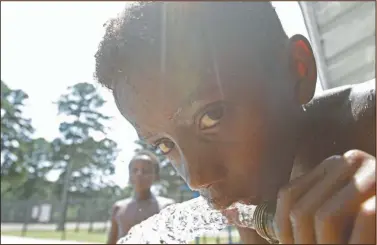  ?? Photos by Terrance Armstard ?? Keeping cool: Jordan Newton, 9, sips water from a hose while swimming at Mattocks Park Pool Friday.