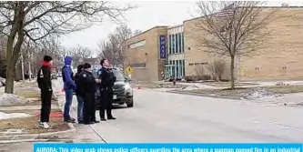  ?? —AFP ?? AURORA: This video grab shows police officers guarding the area where a gunman opened fire in an industrial area in Aurora, Illinois.