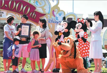  ?? XINHUA ?? A Tokyo Disneyland employee presents a certificat­e to the 700 millionth visitor to the amusement park on Monday.