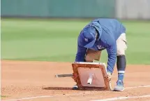  ?? Christian Petersen/Getty Images ?? A member of the Kansas City Royals grounds crew replaces the first base during a break from a spring training game against the Angels at Surprise Stadium on Thursday in Surprise, Ariz. As part of the MLB updated rules, bases are now 18 inches square.