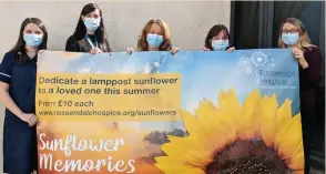  ??  ?? ●● Rossendale Hospice chief executive Irene Smith (centre) with Hospice staff holding a Sunflower Memories banner