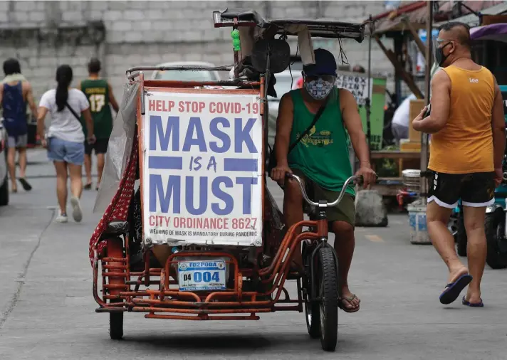  ??  ?? A man rides his pedicab with a slogan to remind people to wear masks to prevent the spread of the coronaviru­s in Manila, Philippine­s yesterday. Covid-19 infections in the Philippine­s surged past 1 million Monday in the latest grim milestone as officials assessed whether to extend a monthlong lockdown in Manila and outlying provinces amid a deadly spike or relax it to fight recession, joblessnes­s and hunger. Photo: AP