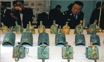  ?? HUO YAN / CHINA DAILY ?? People examine relics on Tuesday that were recovered in a special operation in Xi’an, Shaanxi province. The launch of China’s national internet platform that provides informatio­n about lost or stolen cultural relics will help netizens create even more...