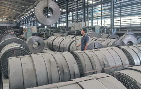  ?? SOMCHAI POOMLARD ?? A worker hoists down a roll steel at a plant in Samut Prakan. Local steel industry has suffered not only from slow economy but high competitio­n from low-priced steel from China.