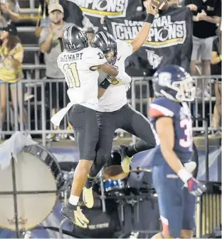  ?? STEPHEN DUNN/ASSOCIATED PRESS ?? UCF freshman QB Darriel Mack Jr., right, is congratula­ted by teammate Cam Stewart (11) after Mack scored his first college TD — as his parents looked on from the stands — in Thursday’s win over UConn.