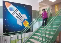  ?? GREG SORBER/JOURNAL ?? Wherry Elementary fifth grade teacher Annette Saiz walks past a Wherry Rockets mural inside the newly rebuilt school.