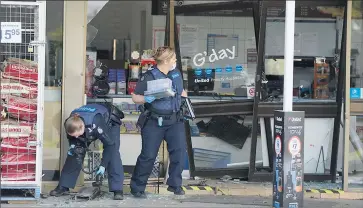  ??  ?? Picking up the pieces: Police gather evidence from the Nagambie service station after a ram-raid last week.