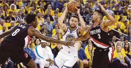 ?? AFP PIC ?? Stephen Curry (centre) of the Golden State Warriors drives to the basket past Al-Farouq Aminu (left) and CJ McCollum of the Portland Trail Blazers on Tuesday.