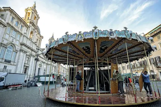  ?? (foto Claudio Guaitoli) ?? L’installazi­one della giostra tra le bancarelle di piazza Navona per la Festa della Befana