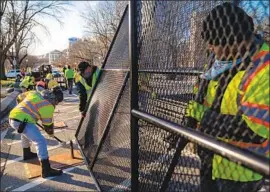  ??  ?? WORKERS put up a security fence near the U. S. Capitol a day after it was broken into by insurrecti­onists demanding that the presidenti­al election be overturned.