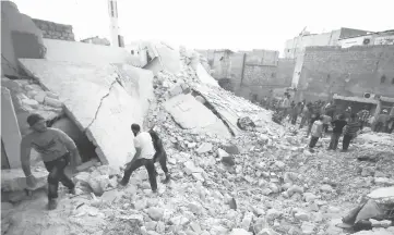  ??  ?? Men inspect damage after an airstrike on Aleppo’s rebel held al-Hallak neighbourh­ood. — Reuters photo