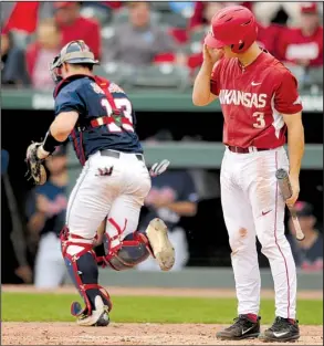  ?? NWA Democrat-Gazette/ANDY SHUPE ?? Ole Miss catcher Cooper Johnson (left) heads to the dugout after Arkansas’ Jared Gates struck out to end the sixth inning of Friday’s first game. The Rebels won 2 of 3 games to clinch the SEC series.