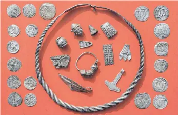  ?? FOTO: DPA ?? Gefunden in einem Acker auf Rügen: Zum Silberscha­tz gehören unter anderem ein gewendelte­r Drahtring, Silberschm­uck, ein Thorshamme­r-Amulett und dänische sowie ottonische Münzen.