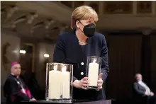  ??  ?? German chancellor Angela Merkel holds a candle during the memorial service in Berlin, Germany