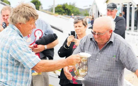  ??  ?? Warren D’Ath presents Horowhenua AP&I Show sheep steward Gilbert Timms with an engraved cup to celebrate Timms’ 60 year involvemen­t with the show.