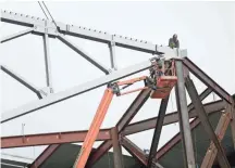  ??  ?? Tom Williams (top) works on the peak as the first roof truss is raised.