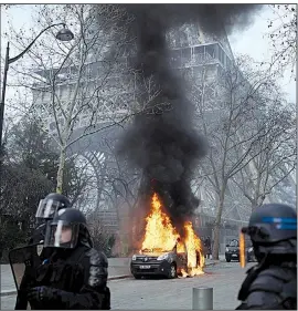  ?? AP/KAMIL ZIHNIOGLU ?? Riot police respond Saturday near the Eiffel Tower in Paris near an anti-terror-squad vehicle that was set on fire by yellow vest protesters. One demonstrat­or’s hand was ripped apart as a group tried to storm the French National Assembly before moving toward the Eiffel Tower.