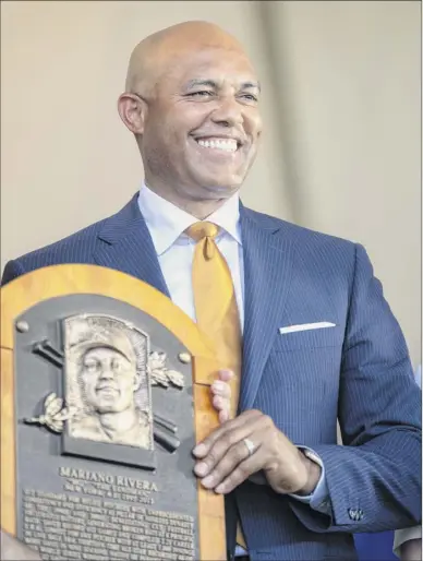 ?? Calla Kessler / The New York Times ?? Former Yankees closer Mariano Rivera holds his plaque during the Baseball Hall of Fame induction ceremony in Cooperstow­n on Sunday. Rivera is the only player elected unanimousl­y to the Hall.