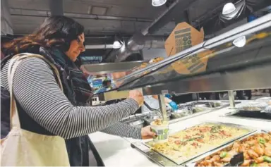  ?? Photos by John Leyba, The Denver Post ?? Jiovanna Toppi fills a container with lobster mac and cheese to take home.