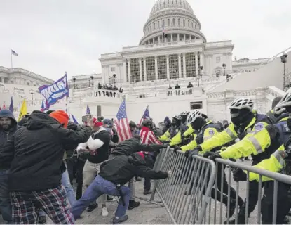  ?? JULIO CORTEZ/AP ?? Trump supporters try to break through a police barrier Jan. 6 at the Capitol.