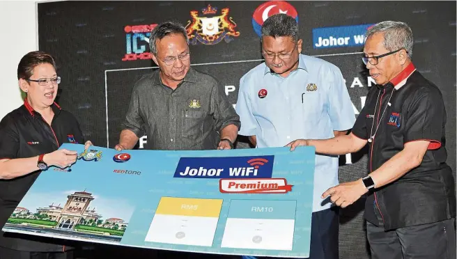  ??  ?? REDtone Engineerin­g and Network Services Sdn Bhd executive director Datuk Ismail Osman (right) presenting a mock rate card to Hasni (second from left) after launching the Johor Premium Wi-Fi service at the Johor Berkemajua­n Expo in Kota Iskandar,...