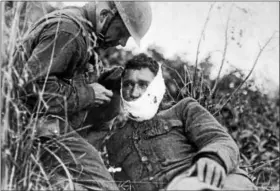  ?? PHOTO COURTESY OF THE NATIONAL ARCHIVES ?? An American soldier wraps another soldier’s head wound at Varennes-en-Argonne, France (September 1918).