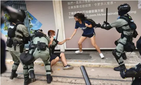  ?? AFP ?? Police chase down a couple wearing masks in the Central district in Hong Kong on Saturday, a day after the city’s leader outlawed face coverings at protests.