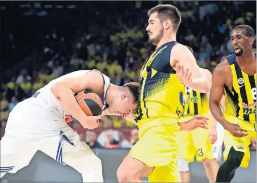  ??  ?? CONTRA UN MURO. Luka Doncic choca con Nikola Kalinic. El Fenerbahçe estuvo muy bien defensivam­ente ante el Real Madrid.