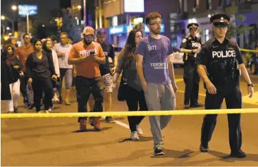  ?? Nathan Denette / Canadian Press ?? Police escort people from the scene of the shooting in the Greektown district of Toronto late Sunday.