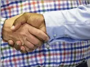  ??  ?? Jimmie Smith, a deacon at First Baptist Church on New Street, shakes hands with Jody Long, a minister at First Baptist Church of Christ on High Place, at First Baptist Church’s Thanksgivi­ng potluck on Nov. 19.