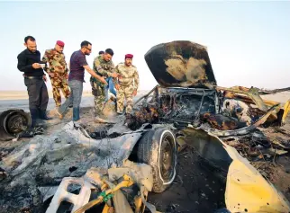  ??  ?? Iraqi security forces inspect the site of a bomb attack at a police checkpoint on a highway near the southern Iraqi city of Nasiriyah on Thursday. (Reuters)