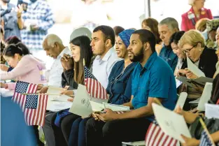  ?? JIM AGNEW/FREELANCE PHOTOS ?? Candidates for citizenshi­p smile while listening to remarks during a naturaliza­tion ceremony in Colonial Williamsbu­rg on Monday. The ceremony recognized 49 people who became new citizens.