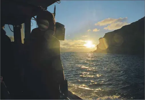  ?? JULIE COLLINS/CAPE BRETON POST ?? The sun rises just off the Bird Islands as skipper Kevin Squires and helper Jonathan Squires haul their first lobster traps of the day.