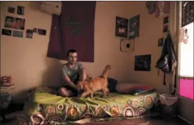  ?? NARIMAN EL-MOFTY — THE ASSOCIATED PRESS ?? In this Thursday photo, Yassin Mohammed sits with a cat in an apartment he shares, in Cairo, Egypt.