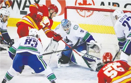  ?? THE CANADIAN PRESS ?? Canucks goalie Thatcher Demko gets his pad on a close-in shot by Flames forward Matthew Tkachuk during second-period NHL action on Monday night at the Scotiabank Saddledome in Calgary. Demko made 27 saves, but the home team prevailed 5-2.