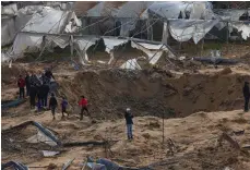  ?? AFP ?? Above, a crater caused by an air strike on a camp in Rafah; right, children walk among the rubble of a destroyed building