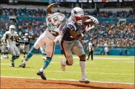  ?? MICHAEL REAVES/ GETTY IMAGES ?? Wide receiver Antonio Brown of the New England Patriots (right) scores on a 20-yard touchdown pass thrown by Tom Brady against the Miami Dolphins on Sunday in Miami. Brown had four catches for 56 yards and the touchdown in his Patriots debut as New England won, 43-0.