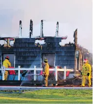  ??  ?? Firefighte­rs douse hot spots Thursday at what remains of the main lodge at the Inverary Resort in Baddeck, N.S.