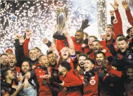  ?? Nathan Denette / Canadian Press ?? Toronto FC captain Michael Bradley hoists the trophy as his team celebrates its win over the Seattle Sounders in the MLS Cup final in Toronto.