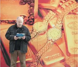  ?? SEAN GALLUP/ GETTY IMAGES ?? A man stands in front of a shop that buys and sells gold in Berlin, Germany. Gold prices reached a two- year low this week and many gold mining companies are feeling a severe squeeze on profits.