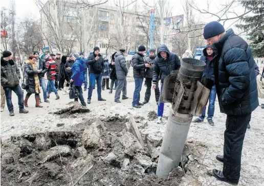  ?? VOLODY MYR SHUVAYEV / AFP / Gett y Imag es ?? Civilians look at a missile embedded in the street after shelling in the eastern Ukrainian city of Kramatorsk on Tuesday. At
least six were killed and 21 were wounded in a rocket attack on Ukraine’s military headquarte­rs, local authoritie­s said.