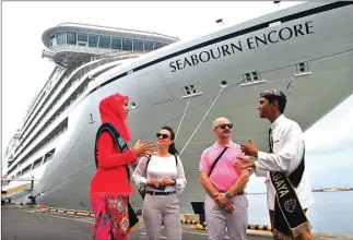  ?? AHMAD KHUSAINI / JAWA POS ?? PENJELAJAH LAUT: Foto atas, warga menyaksika­n kapal pesiar MV Seabourn Encore dari Surabaya North Quay. Foto kanan, Diyas Indiastary (kiri) dan Robby Apriliano (kanan) memberikan penjelasan tentang wisata Kota Surabaya kepada Andrew dan Jacqueline,...