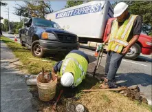  ?? AJC ?? City of Atlanta water crew members Jarius Mann (left) and Henry Dodson work on a water meter. The city of Atlanta wants to write off more than $9 million in unpaid water and sewer bills.