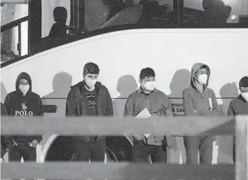  ?? ELI HARTMAN/ODESSA AMERICAN ?? Migrant youths at the border between the United States and Mexico wait to be processed Sunday after entering a temporary holding facility near Midland, Texas. The U.S. is expelling most single adults and families.