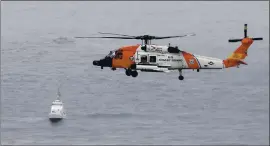  ?? PHOTOS BY DENIS POROY — THE ASSOCIATED PRESS ?? A U.S. Coast Guard helicopter flies over boats searching the area where a boat capsized just off the San Diego coast Sunday. Three people died at the scene.