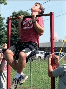  ??  ?? Incoming freshman softball player Auna Rolfe flips a tire, while rising senior football player Jacob Flanagan does Marine-style pull-ups as part of boot camp drills held for LFO athletes this past Tuesday. More than 120 LFO athletes took part in the event, which was run by the Marines recruitmen­t center of West Georgia. (Messenger photo/Scott Herpst)