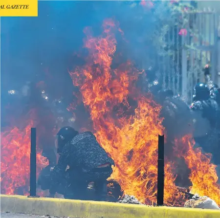  ?? JUAN BARRETO / AFP / GETTY IMAGES ?? Two police motorbikes burn after being hit by an improvised explosive device placed by anti-government activists during a protest in Caracas against the Venezuelan election on Sunday. Deadly violence erupted nationwide in the wake of the controvers­ial...